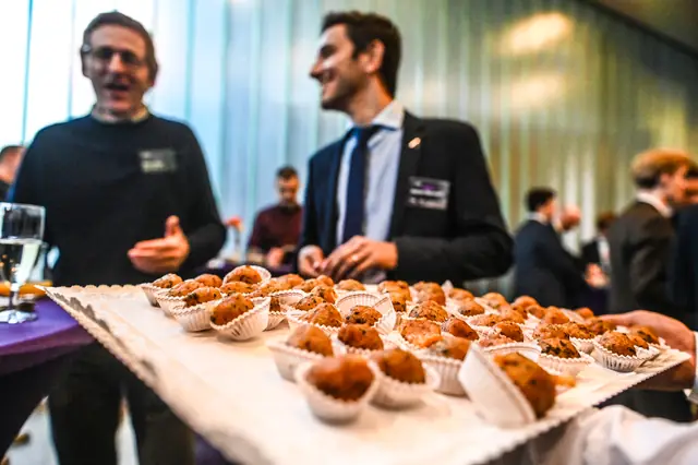 A tray of bites making the rounds, with guests laughing behind it.