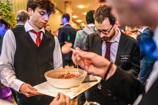A waiter offering a bowl of bites.
