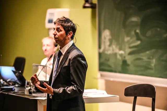 A speaker at the lectern, mid-sentence.