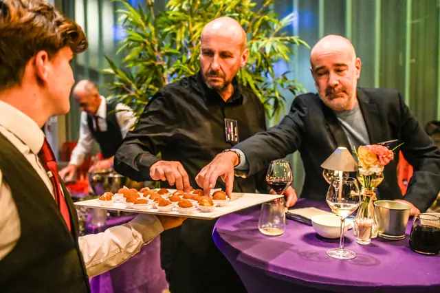Guests reaching for bites from a tray.